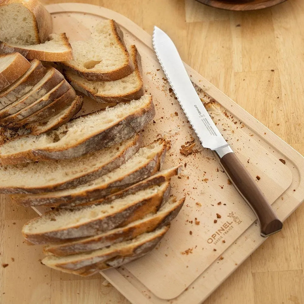 A slicing bread on a beige wooden cutting board with a serrated knife placed alongside, all presented on a wooden surface.