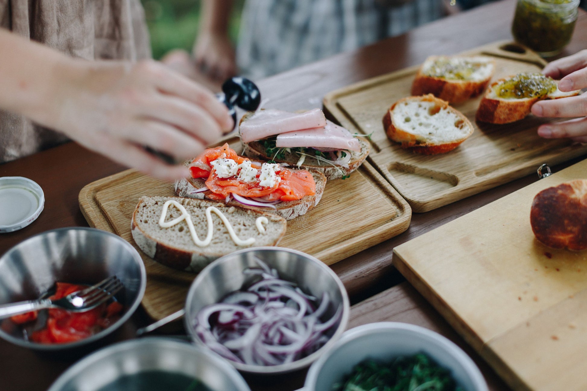 SnowPeakDiningLifestyle Oak Charcuterie Plate Stainless Bowls Sandwiches Salmon Cheese Mayo Mint Jelly Red Onion Bell Peppers Ham 